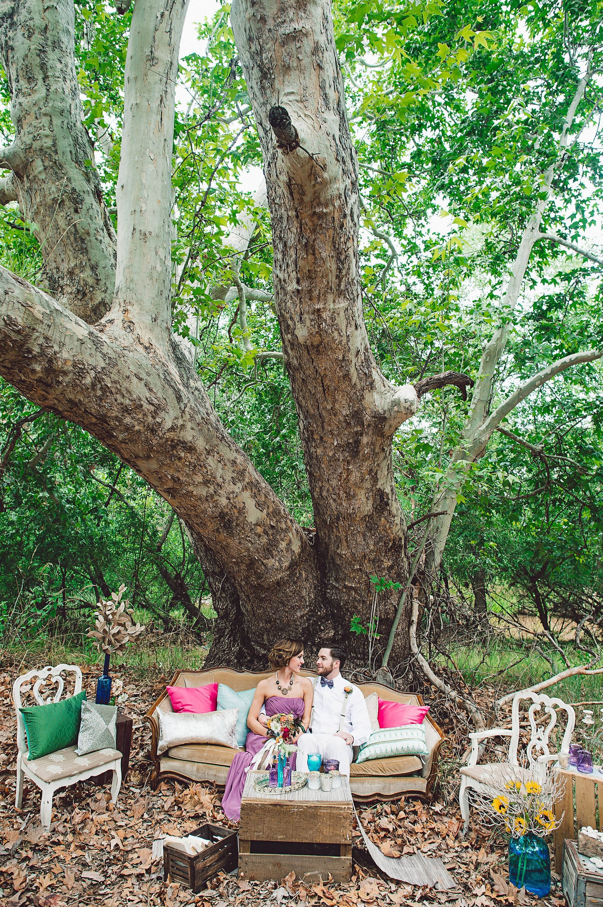 Bride and groom on a couch under a tree