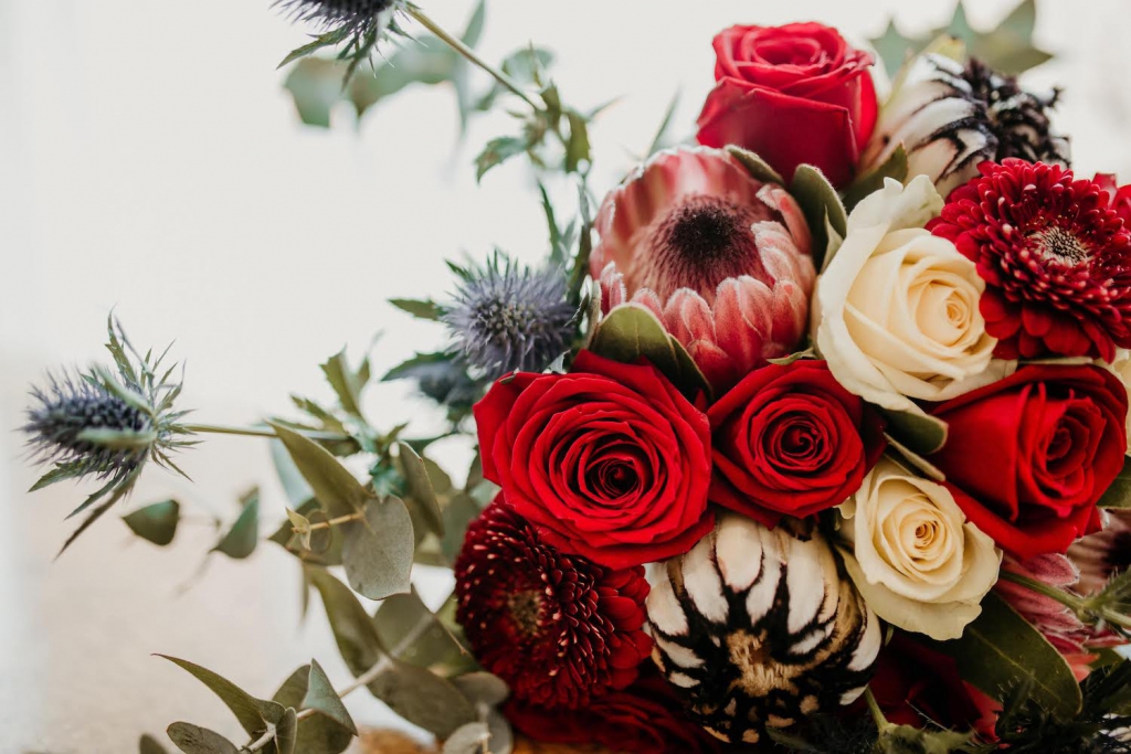 bridal bouquet with blue thistle, and red and champagne roses