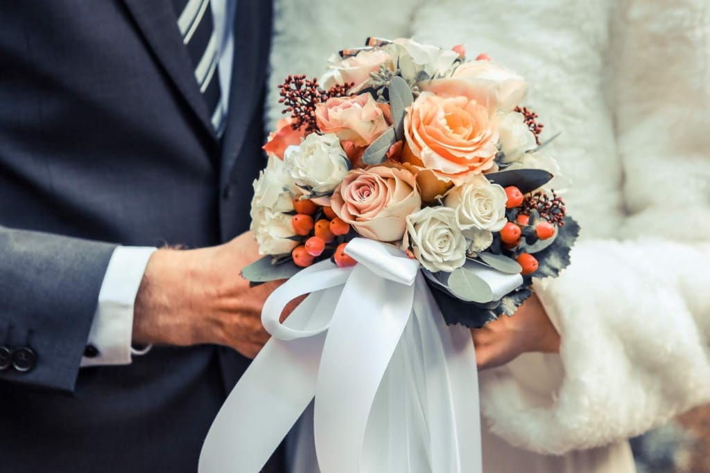bride holding bouquet with blush roses, berries, and eucalyptus leaves, tied with white ribbon