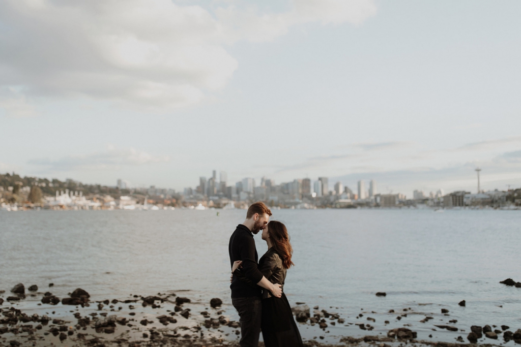 couple embracing at gas works park in seattle with downtown skyline in the background