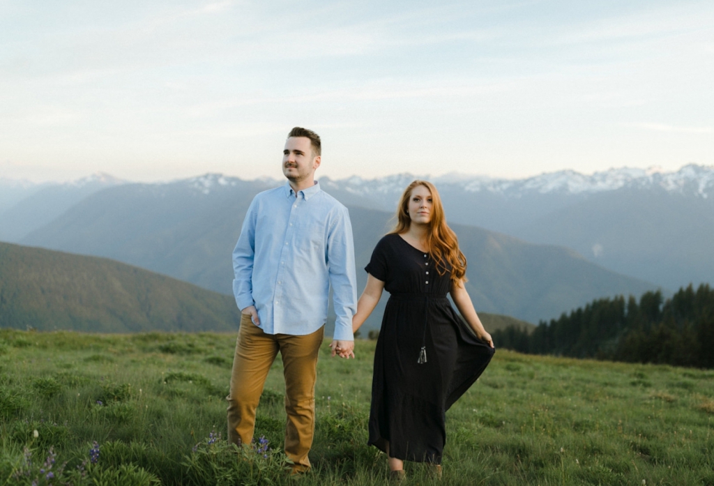 couple holding hands at hurricane ridge in seattle with mountains in the background