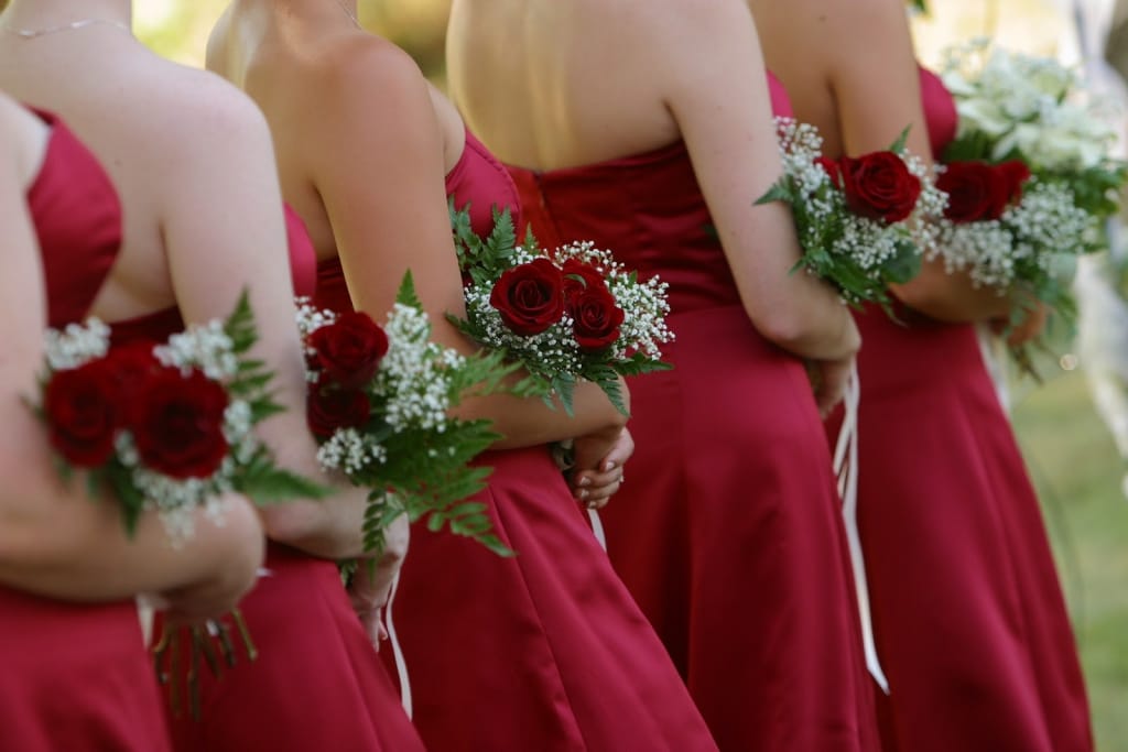 Bridesmaids in crimson dresses with matching bouquets