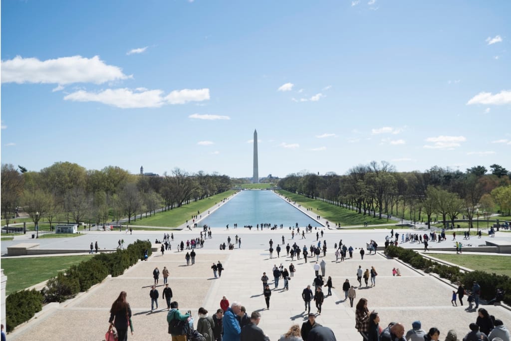 crowd gathers in front of national mall under blue sky as proposal setting